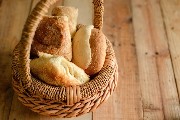 Panier en osier avec pains sucrés sur table en bois. Fond bleu.