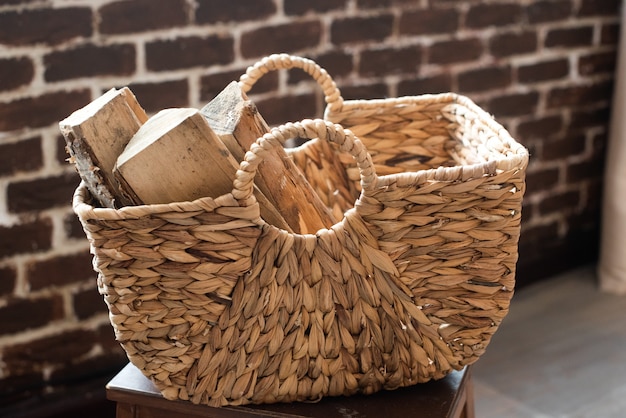 Un panier en osier en papier vigne rempli de bois de chauffage. recyclage, éco, matériaux naturels, respectueux de l'environnement. style bohème, rustique, confortable.