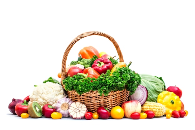 Photo panier en osier plein de fruits et légumes biologiques isolés