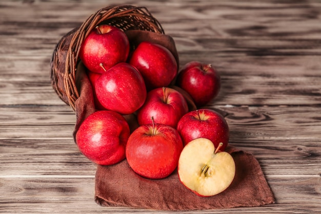 Panier en osier avec des pommes rouges fraîches sur fond de bois