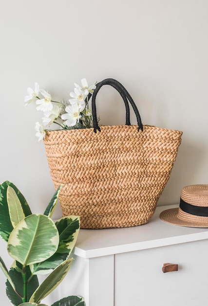 Panier de paille en osier avec un bouquet de fleurs sur un tableau blanc