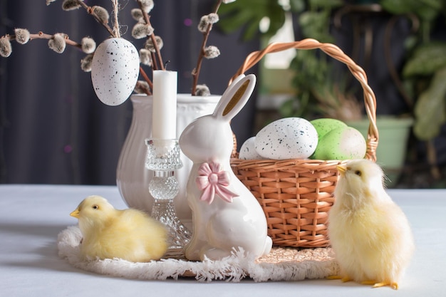 Un panier de Pâques avec des œufs colorés et un lapin de Pâque un bouquet de saules moelleuses dans un vase
