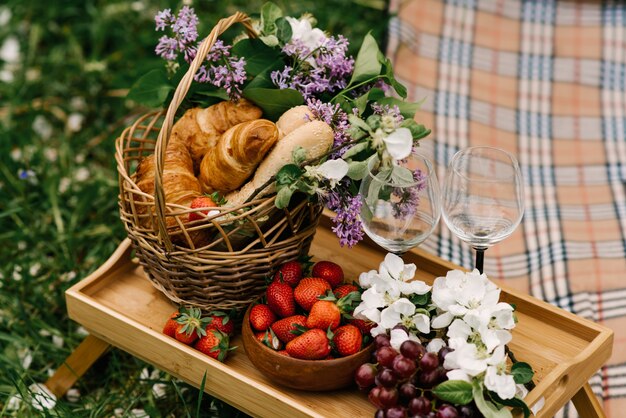 Panier pique-nique avec des fraises, des raisins et des petits pains sur l'herbe verte dans le jardin