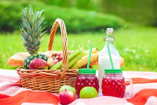 Panier pique-nique, fruits, jus en petites bouteilles, pommes, été ananas, repos, plaid, herbe