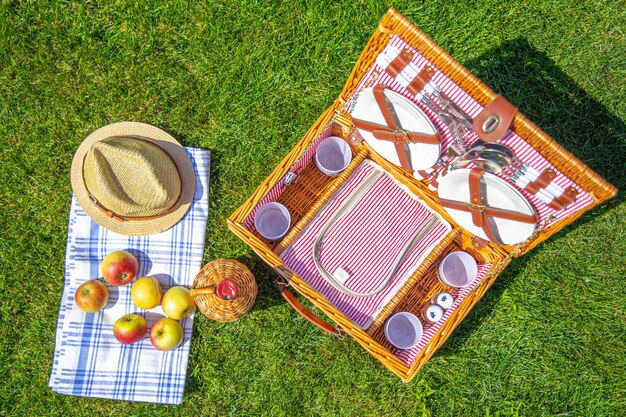 Panier pique-nique sur une pelouse verte et ensoleillée dans le parc