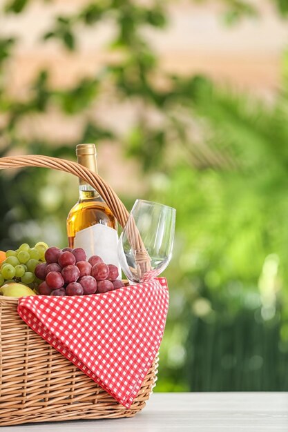 Panier pique-nique avec produits et vin sur table sur fond flou espace pour le texte