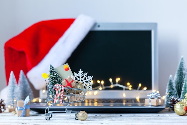 Panier plein de coffrets cadeaux et arbre de Noël sur le clavier d'un ordinateur portable Concept achats en ligne et vente de vacances