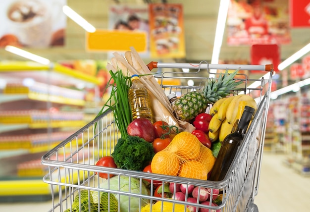 Panier plein avec divers produits d'épicerie sur l'arrière-plan