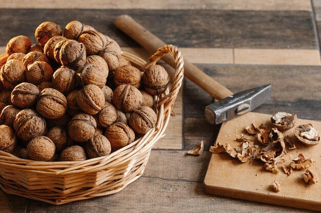 Panier plein de noix en coquille et marteau sur un fond de bois Produit sain naturel
