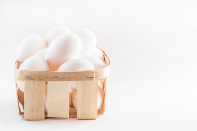 Panier plein d'oeufs frais sur fond blanc