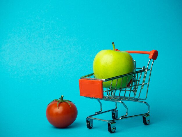 Panier avec pomme et tomate sur fond bleu