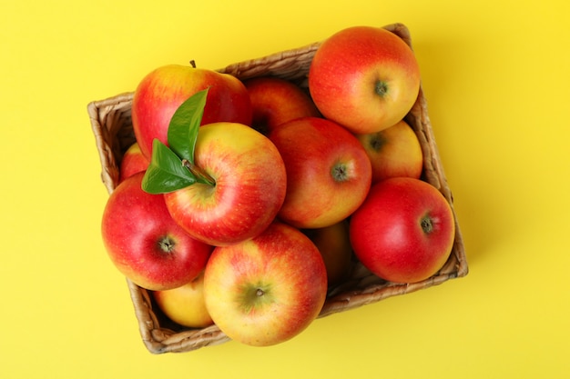 Panier avec des pommes rouges sur fond jaune