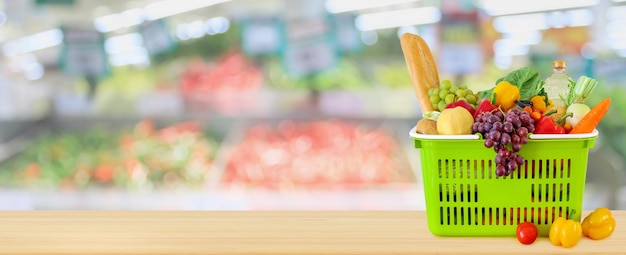 Panier rempli de fruits et légumes sur table en bois avec fond de supermarché