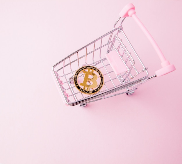 Un panier d'un supermarché, bitcoin sur un fond en bois. Internet, crypto-monnaie.