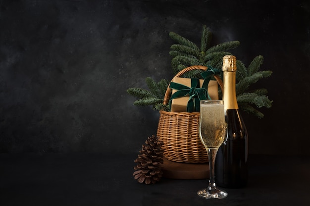 Panier de vacances de Noël avec verre de vin mousseux et cadeau sur l'espace noir