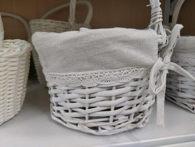 Paniers décoratifs en osier sur une étagère dans un magasin Jolis paniers peints en blanc Sac textile Cadeau élégant pour Pâques Élément de décoration de l'intérieur d'un appartement une maison de campagne ou un jardin de printemps