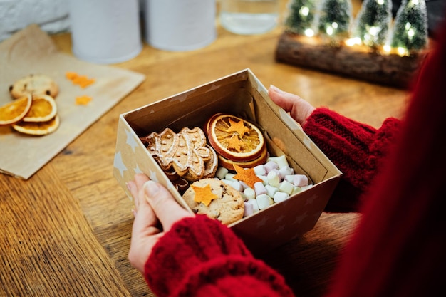 Paniers sucrés faits maison de noël dans les mains des femmes femme hsnds tenant une boîte-cadeau sucrée de noël