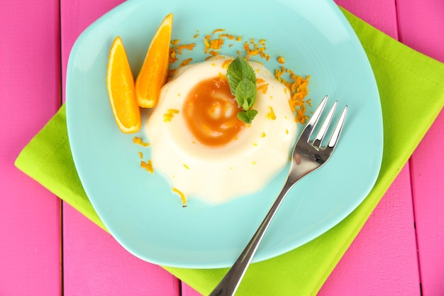 Panna Cotta au zeste d'orange et sauce au caramel sur fond de bois de couleur