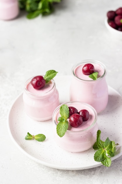 Panna cotta aux cerises avec cerises fraîches et menthe en pots