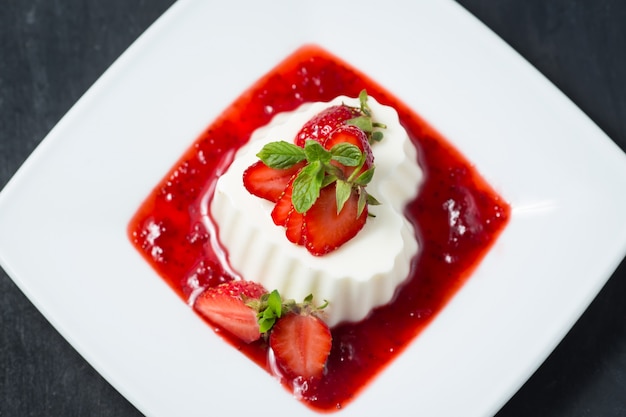 Panna cotta à la fraise sur une assiette blanche.