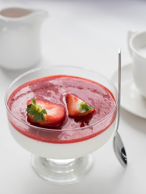 Panna cotta avec sauce aux fraises et baies de fraises dans un bol sur la table et fond blanc