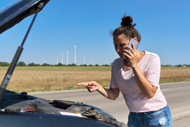 Photo panne de voiture, femme malheureuse sur la route avec capot de voiture ouvert parlant au téléphone mobile. service de réparation automobile, transport, appel de dépanneuse