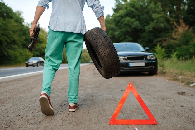 Panne de voiture, l'homme met le pneu de secours.