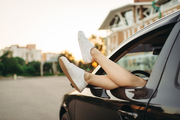 Panne de voiture, jambes féminines qui sortent de la fenêtre