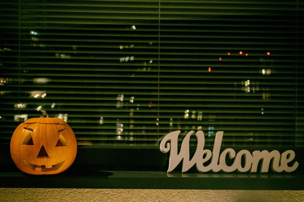 Photo un panneau d'accueil et une citrouille d'halloween sur le seuil de la fenêtre