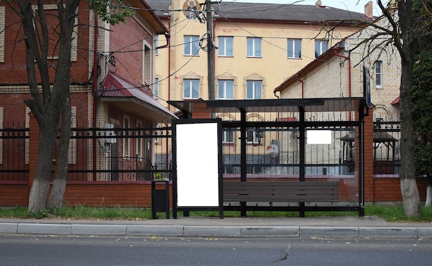 Panneau d'affichage blanc vertical à un arrêt de bus en verre un jour d'été dans une rue de la ville