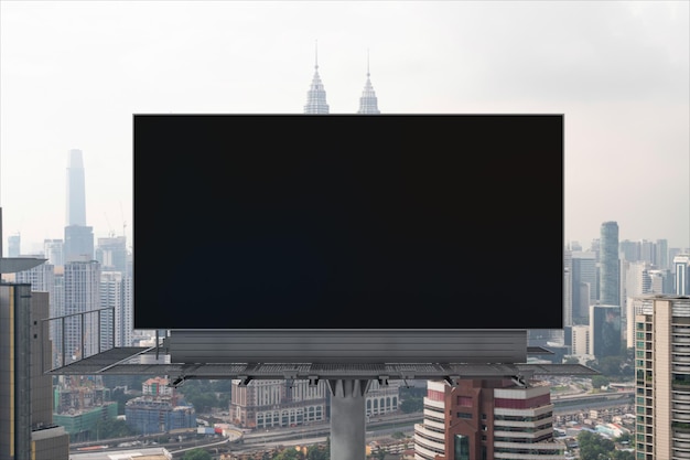 Panneau d'affichage routier noir vierge avec fond de paysage urbain de Kuala Lumpur à l'heure du jour Affiche publicitaire de rue maquette rendu 3D Vue de face Concept de marketing pour promouvoir ou vendre des services ou des idées