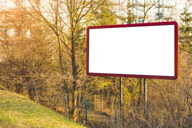 Photo panneau d'affichage vide ou grand tableau avec petite forêt et appartements. vide publicitaire