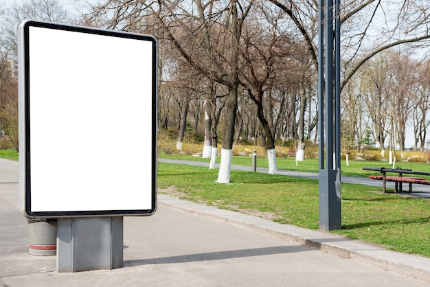 Panneau d'affichage vide ou lightbox sur la rue verte de la ville avec fond isolé blanc