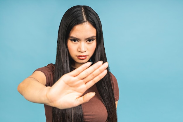 Panneau d'arrêt Femme asiatique concernée montrant un signe de croix disant non sensibiliser debout isolé sur fond bleu