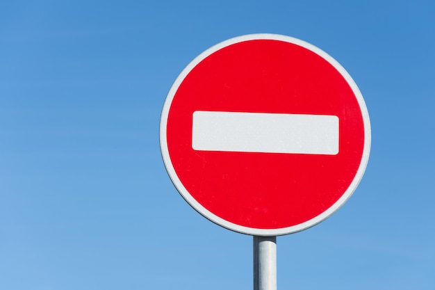 Panneau d'arrêt routier rond, sur un poteau contre le ciel.