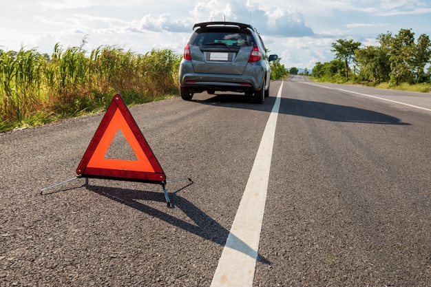 Panneau d'arrêt d'urgence et voiture en panne sur la route