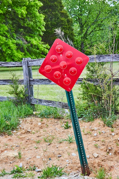 Panneau d'avertissement de diamant signalant une chaussée sans issue à côté d'un patch de terre et d'une vieille clôture de route de campagne