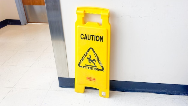 Un panneau d'avertissement jaune se trouve sur un mur dans un couloir.