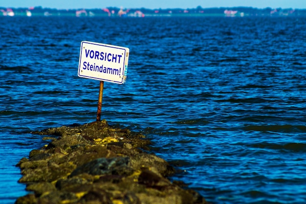 Photo un panneau d'avertissement sur un rocher au bord de la mer