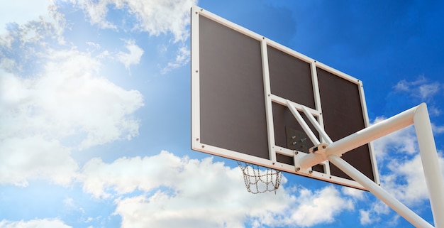 Panneau de basket-ball avec un panier fait de chaînes de fer, gros plan contre le ciel bleu. Espace de copie. Vue en contre-plongée