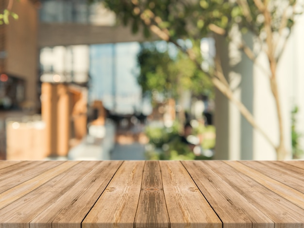 Photo panneau de bois table basse vide sur fond flou. perspective table en bois brun sur le flou dans l'arrière-plan du café - peut être utilisé maquette pour l'affichage des produits de montage ou la conception graphique de conception graphique.