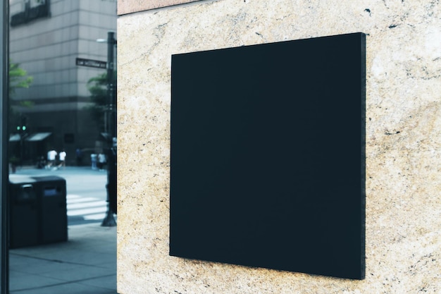 Un panneau carré noir avec un espace vide pour votre logo sur le mur en marbre d'un centre commercial moderne