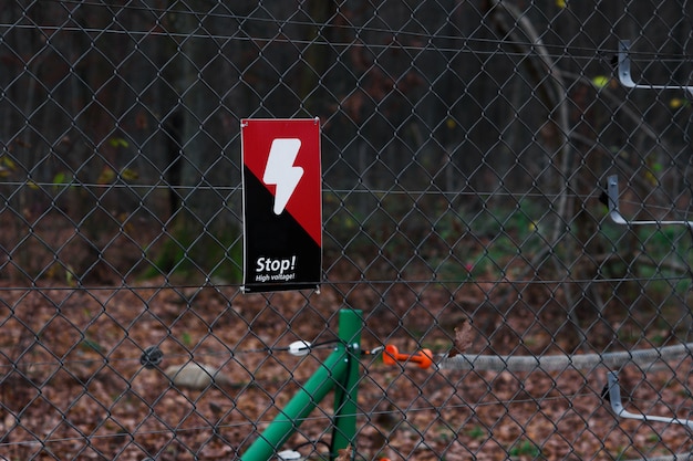 Panneau de danger sur la grille métallique en forêt