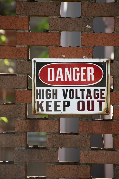 Un panneau d'exclusion à haute tension sur un mur de briques rouges