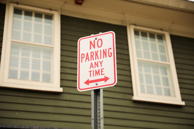 Un panneau indiquant qu'il est interdit de se garer à tout moment en lettres rouges.