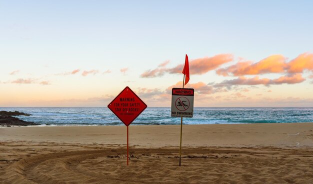 Photo un panneau d'information sur la plage contre le ciel au coucher du soleil