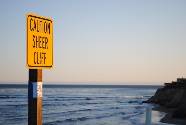 Un panneau d'information sur la plage contre un ciel dégagé