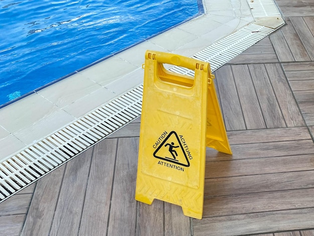 Panneau jaune sol mouillé près de la piscine avec de l'eau pour la baignade et la détente dans un hôtel au chaud