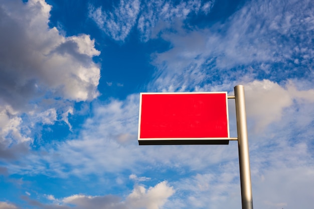 Le panneau publicitaire rouge contre le ciel bleu