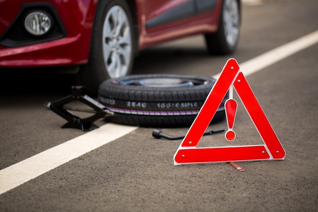 Panneau routier avec une voiture cassée, une roue de secours et des outils